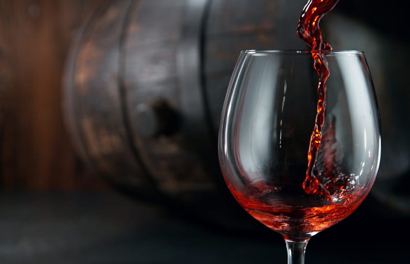 fotografia-copa-añadiendo-vino-tinto-bierzo-al-fondo-una-cuba